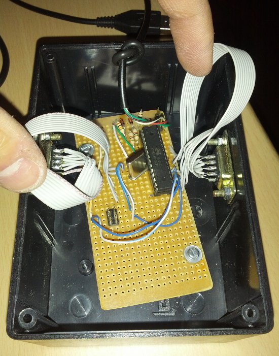 Picture of the plastic box with the circuit board screwed inside, the two DE9 connectors, and the USB cable.